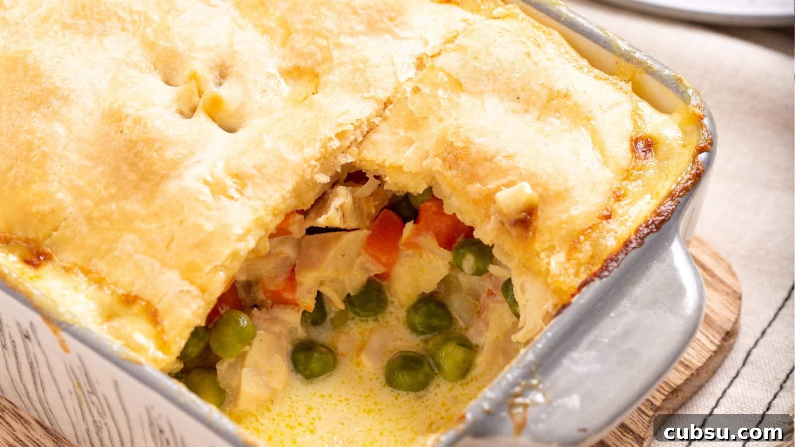 17 Timeless Grandma Recipes You Need to Try Now 6 A freshly baked chicken pot pie with a golden crust and a portion scooped out, revealing the creamy filling with vegetables.