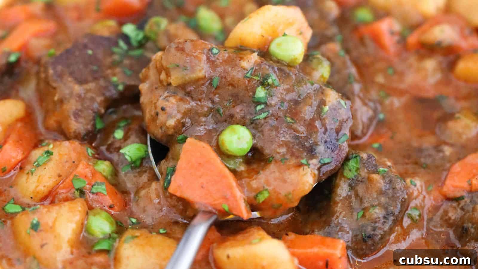 17 Timeless Grandma Recipes You Need to Try Now 7 A close-up of a stew with beef chunks, carrots, peas, and potatoes, garnished with herbs.