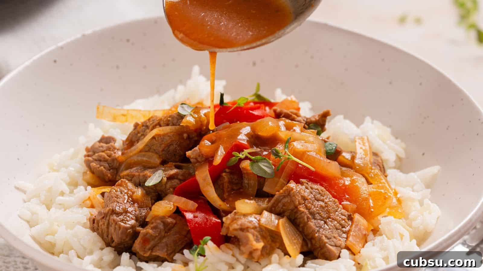 17 Timeless Grandma Recipes You Need to Try Now 9 Sauce being poured over a bowl of beef and bell pepper stir-fry served on white rice.