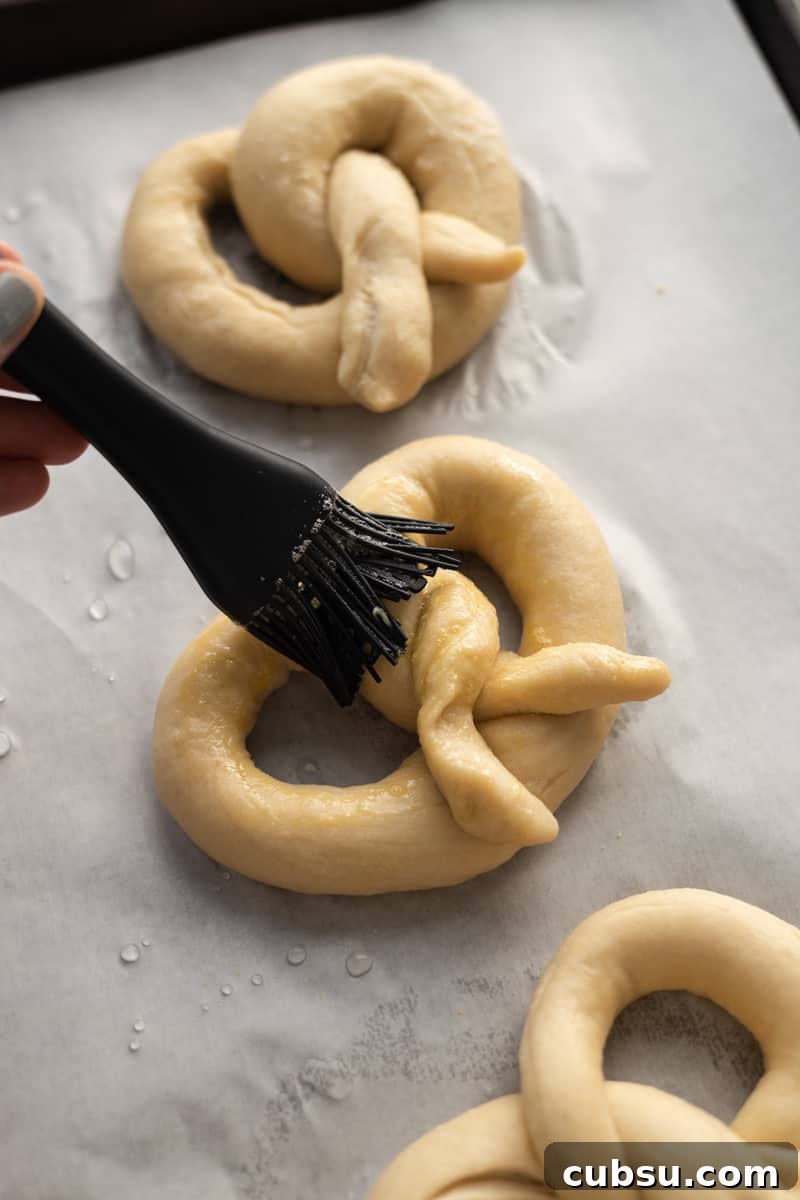 Crispy Sourdough Discard Pretzels: Tangy Soft-Baked Recipe 12 Pretzel being brushed with egg wash.