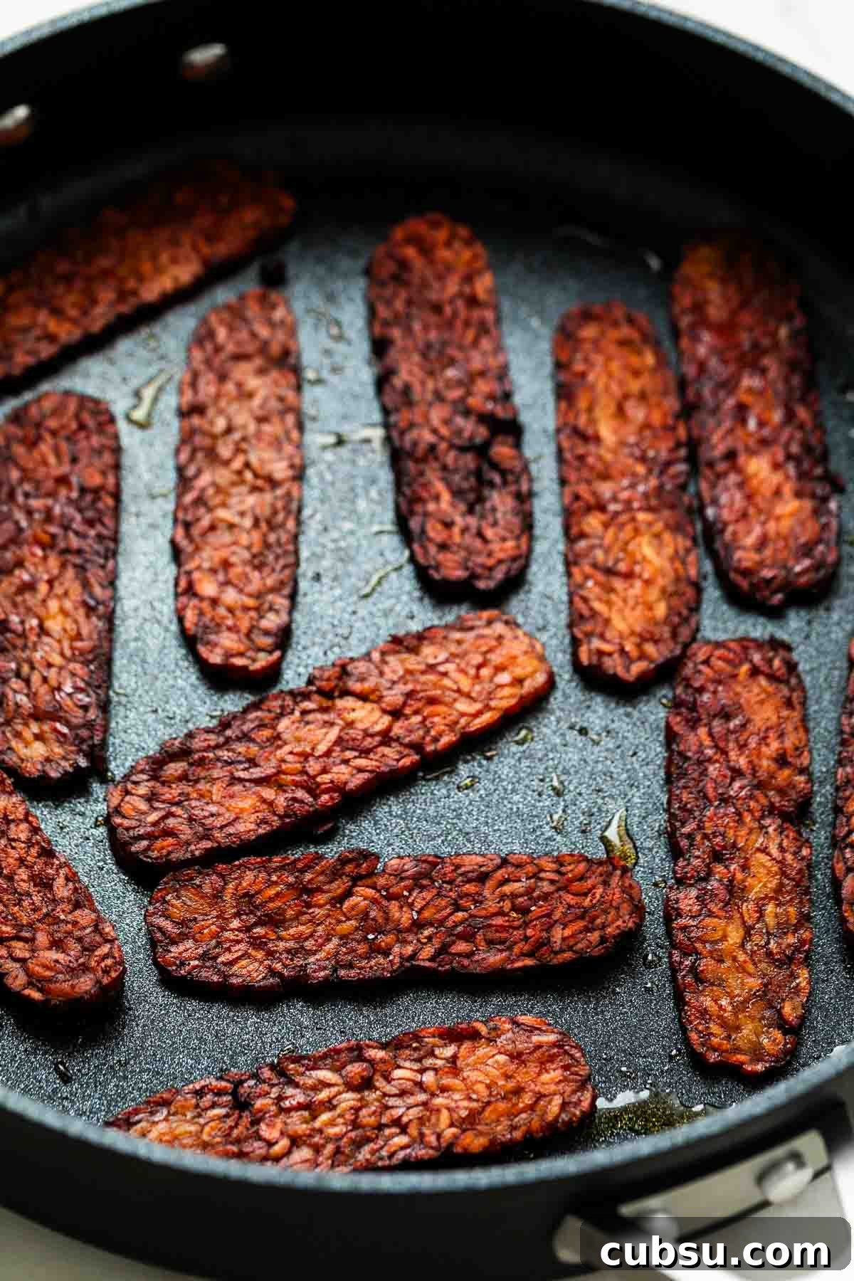 Crispy Tempeh Bacon Recipe: Smoky Vegan Bacon Alternative 8 Cooked tempeh bacon in a large pan.
