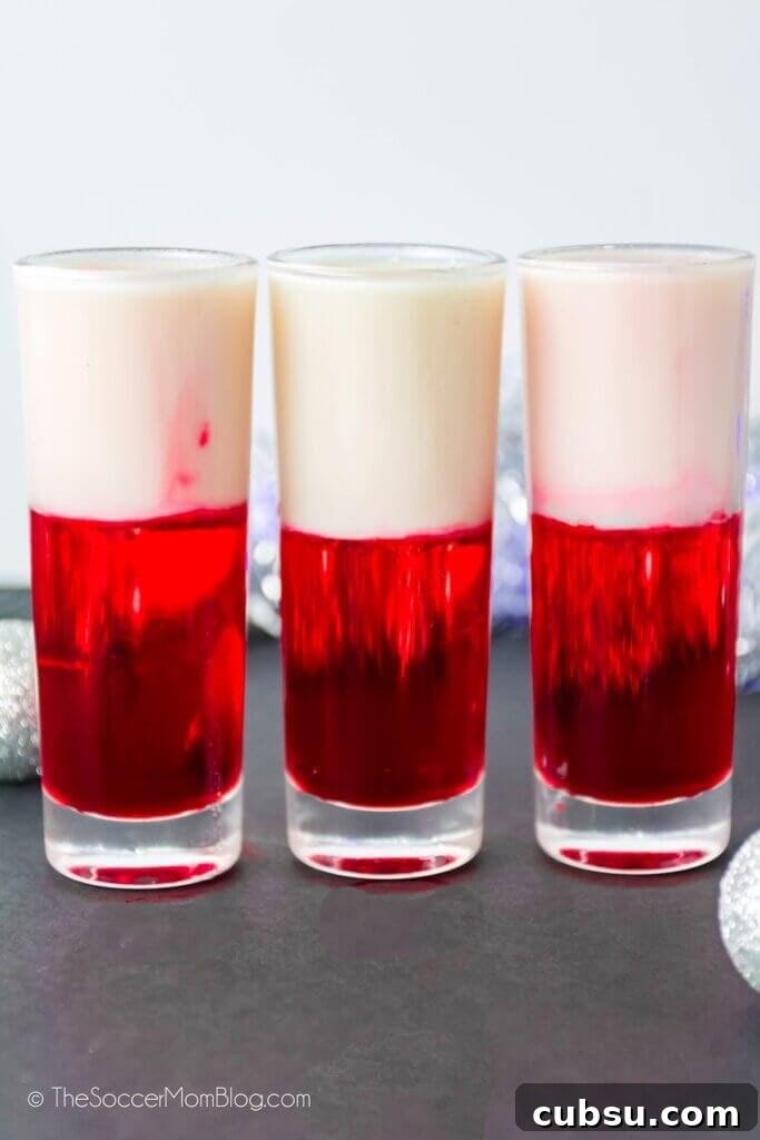 Festive Tipsy Santa Shooters Recipe for Holiday Parties 3 3 shot glasses with red and white layered Santa themed shooters