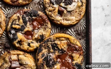 Chewy Oreo Chocolate Chip Cookies Recipe for Ultimate Indulgence 13 Freshly baked Oreo chocolate chip cookies on a cookie sheet surrounded by Oreo crumbs.