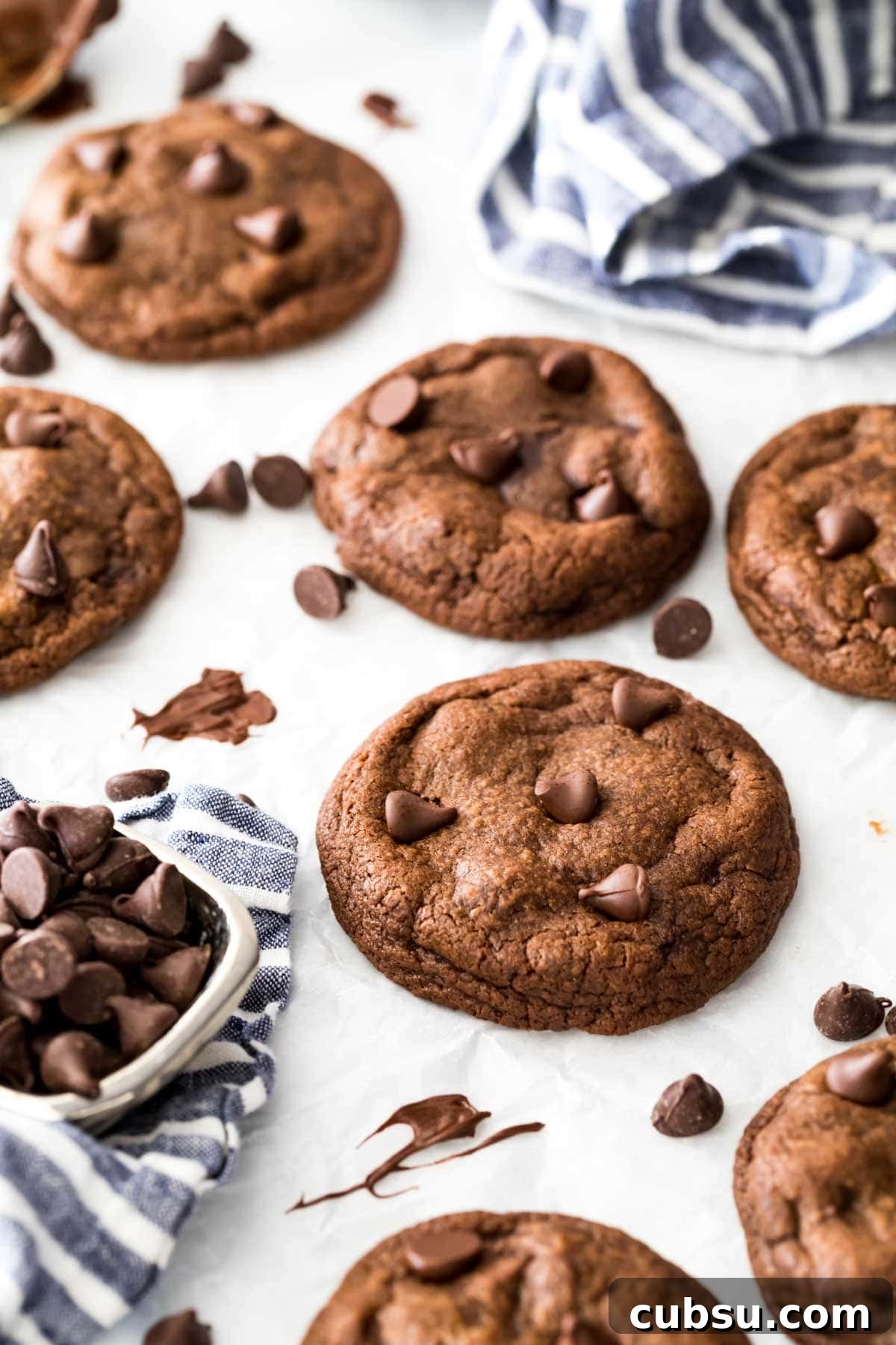 Chewy Fudge Chocolate Cookies Recipe 5 overhead view of fudge cookies on a white surface surrounded by chocolate chips