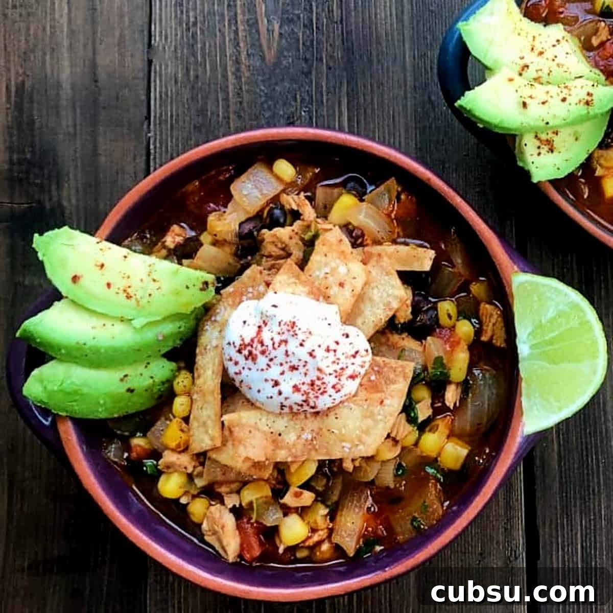 bowl or homemade tortilla soup with sour cream and avocado topping.