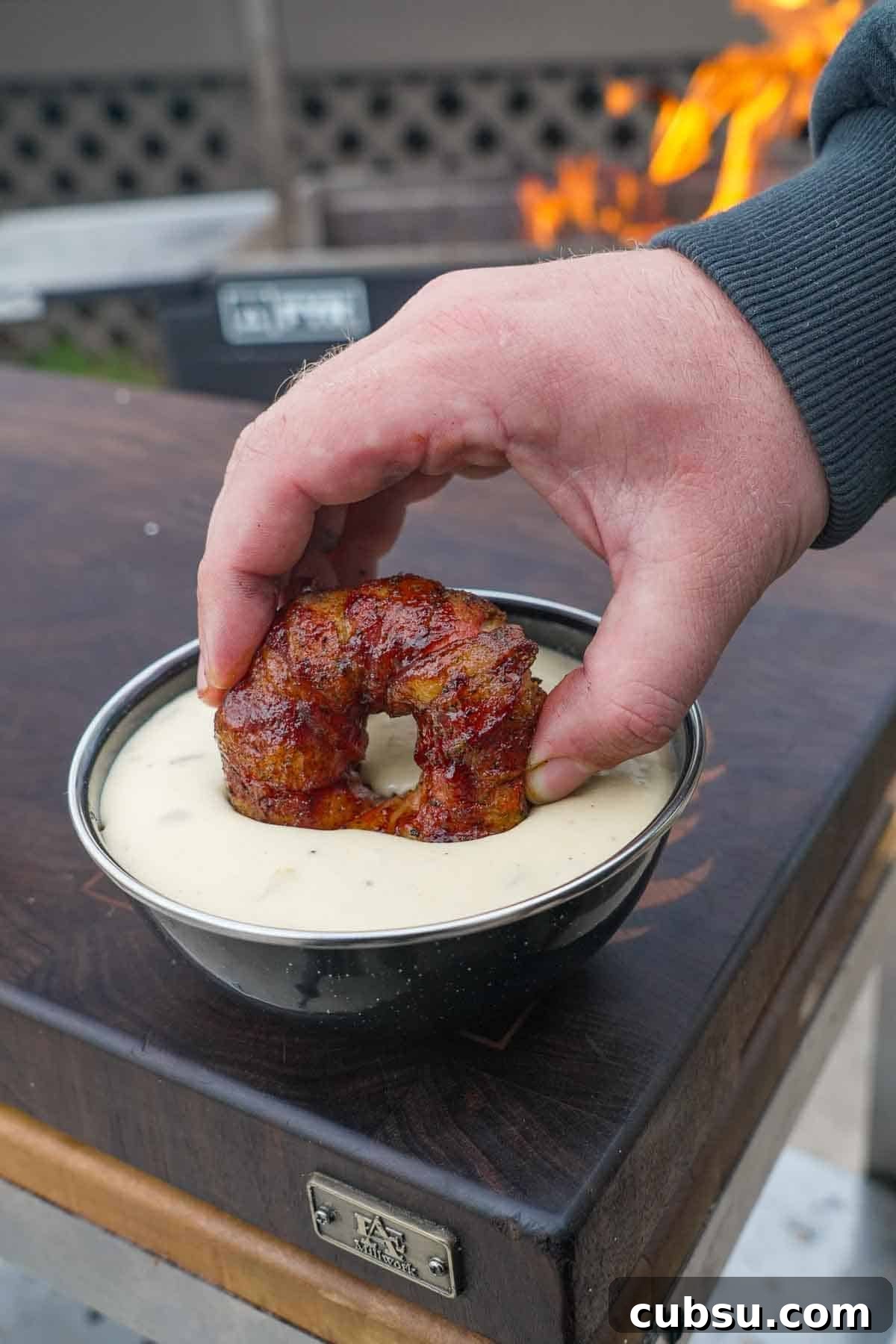 Crispy Chorizo-Stuffed Onion Rings Recipe 3 Dipping a chorizo stuffed onion ring wrapped in bacon in homemade queso in a bowl