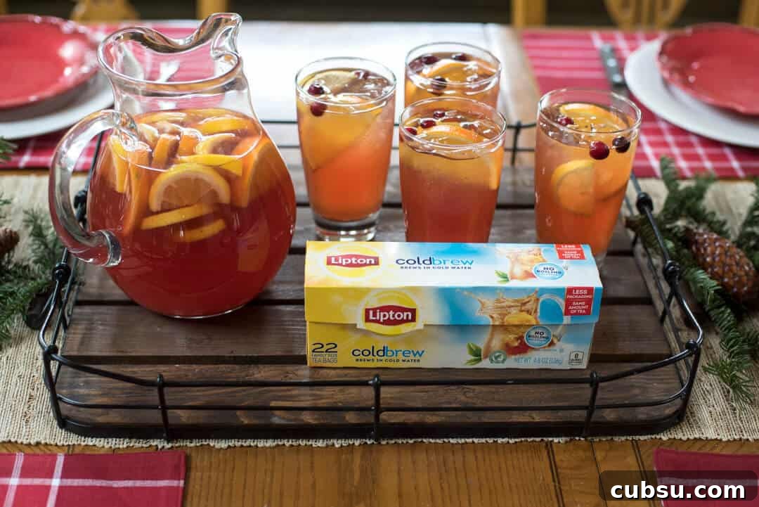 Lipton Cold Brew Tea Bags on a wood tray with glasses and a pitcher of Cranberry Citrus Iced Tea.