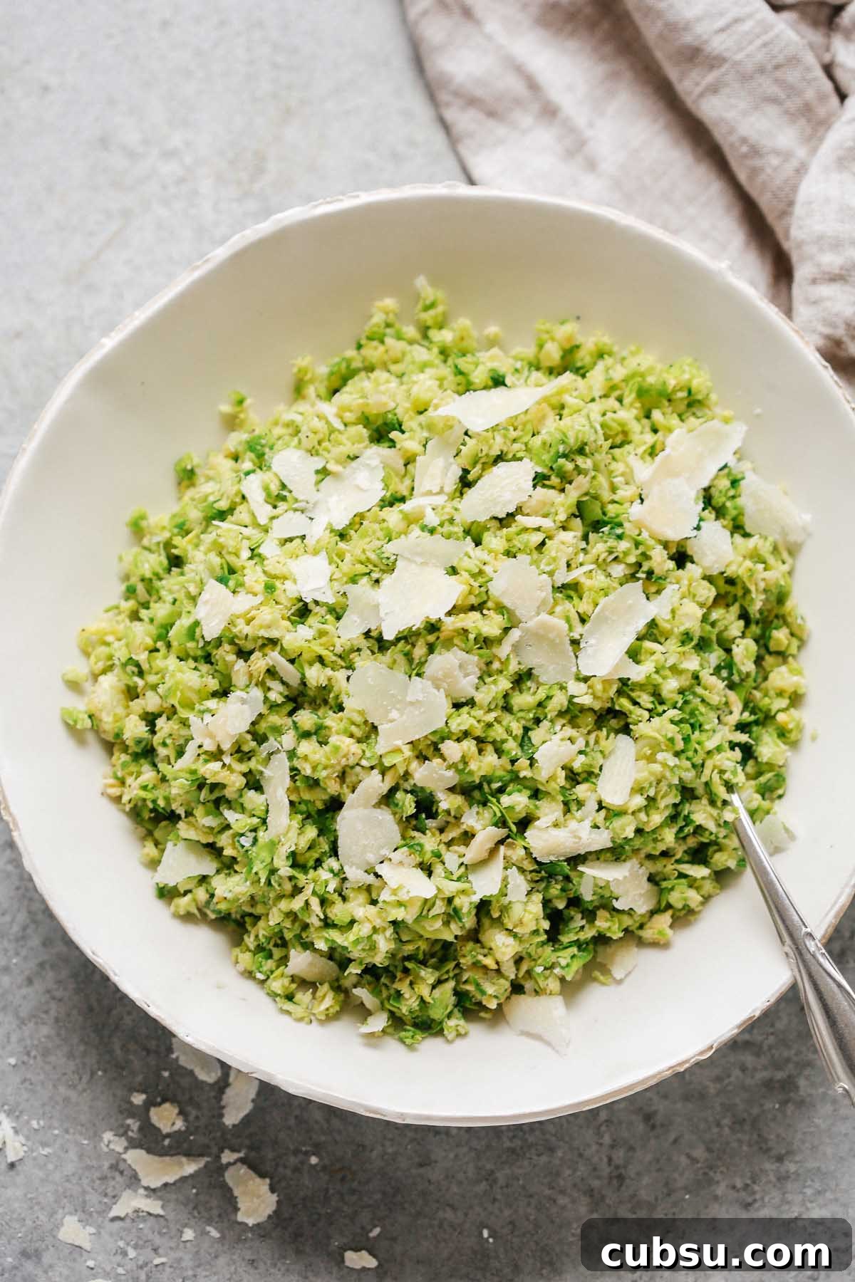 Crispy Parmesan Brussels Sprouts Salad with Lemon Vinaigrette 4 close up of a Parmesan Brussels Sprouts Salad with a spoon and shaved parmesan on top
