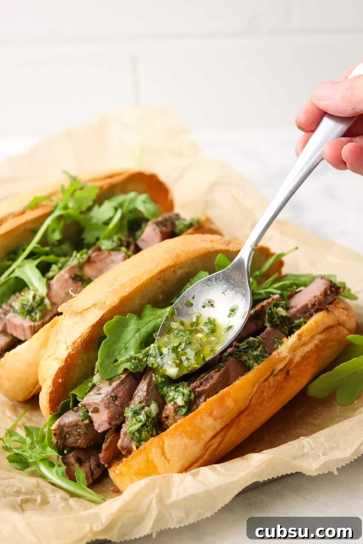 Juicy Steak Sandwich with Fresh Chimichurri Sauce 8 spooning chimichurri on the steak in the sandwich