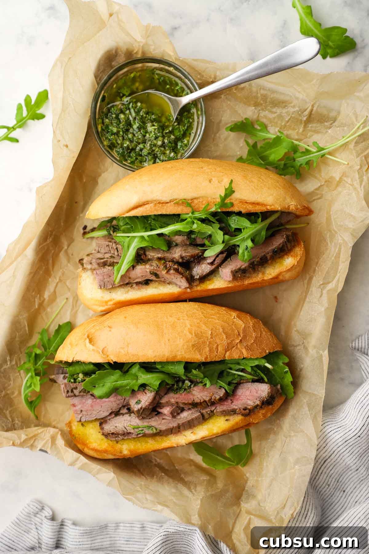 Juicy Steak Sandwich with Fresh Chimichurri Sauce 9 overhead view of two steak sandwiches with chimichurri