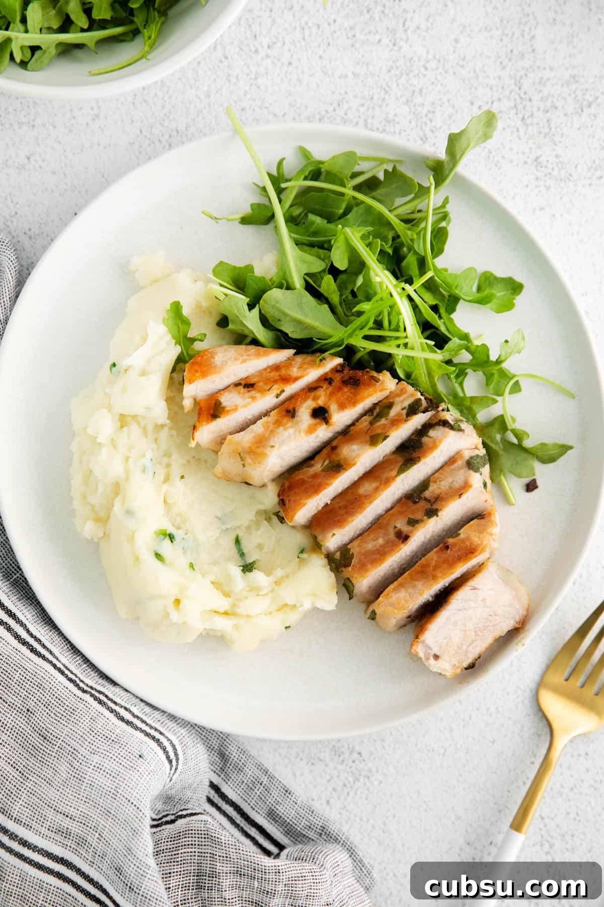 Juicy Grilled Boneless Pork Chops with Garlic Herb Marinade 5 one cut pork chop on a plate with mashed potatoes and greens