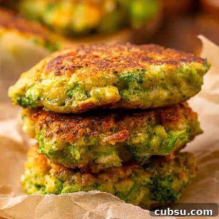 Close up of pan fried broccoli fritters with feta cheese, stacked and showing a golden crust and tender texture inside.