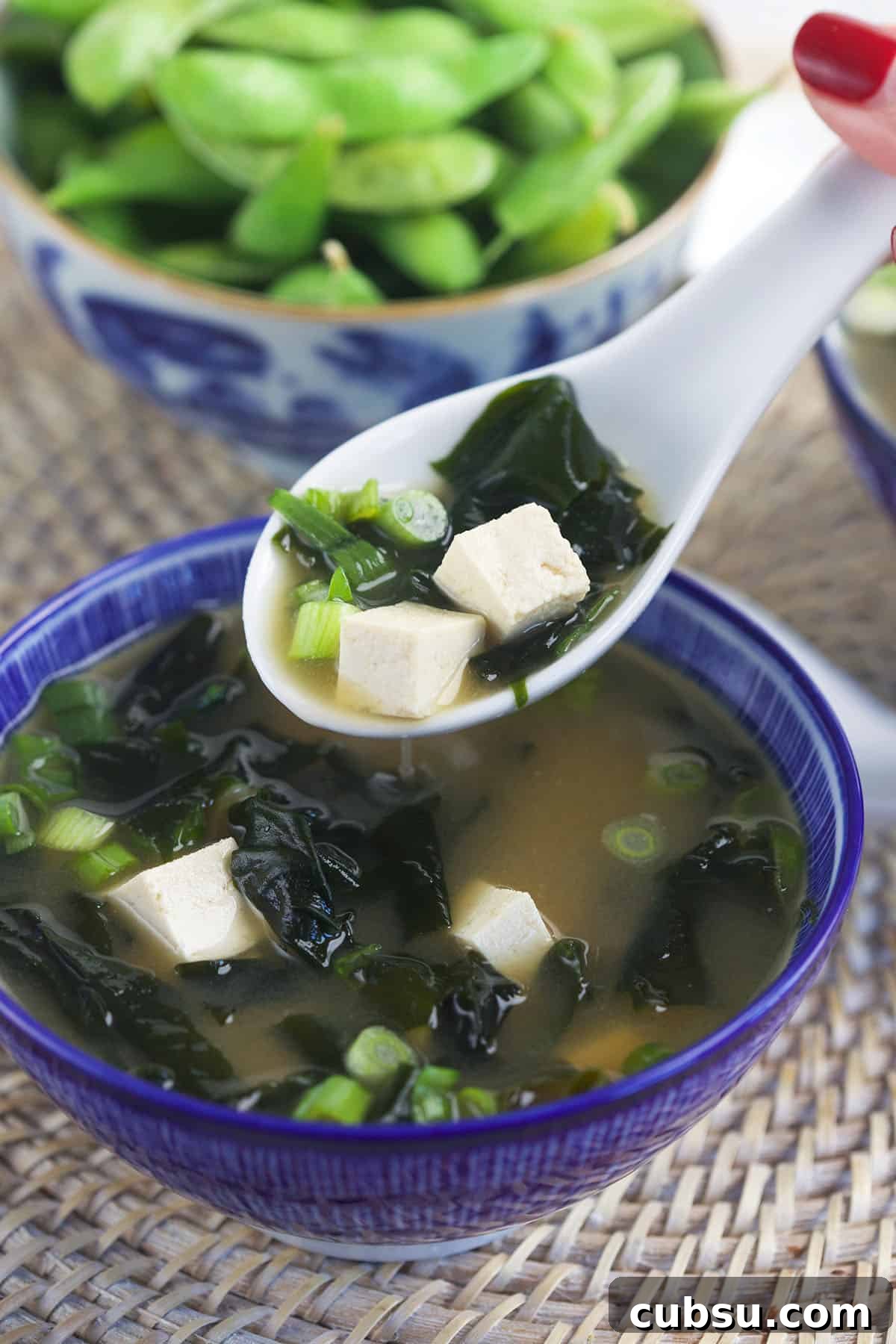 Authentic Miso Soup Recipe for Fast Weeknight Meals 5 A white spoon is lifting a portion of soup from a bowl.
