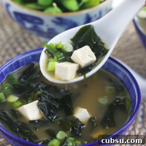 Authentic Miso Soup Recipe for Fast Weeknight Meals 6 A white spoon is lifting a portion of soup from a bowl.
