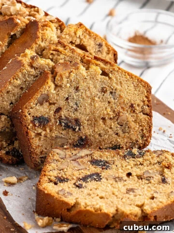 Sliced date walnut loaf on white paper on a wooden board. Striped background.