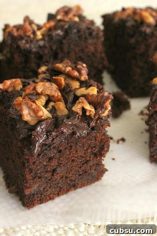 Decadent Chocolate and Date Cake Recipe for Moist Loaves 19 Chocolate date walnut cake squares on a white surface. Close up image.