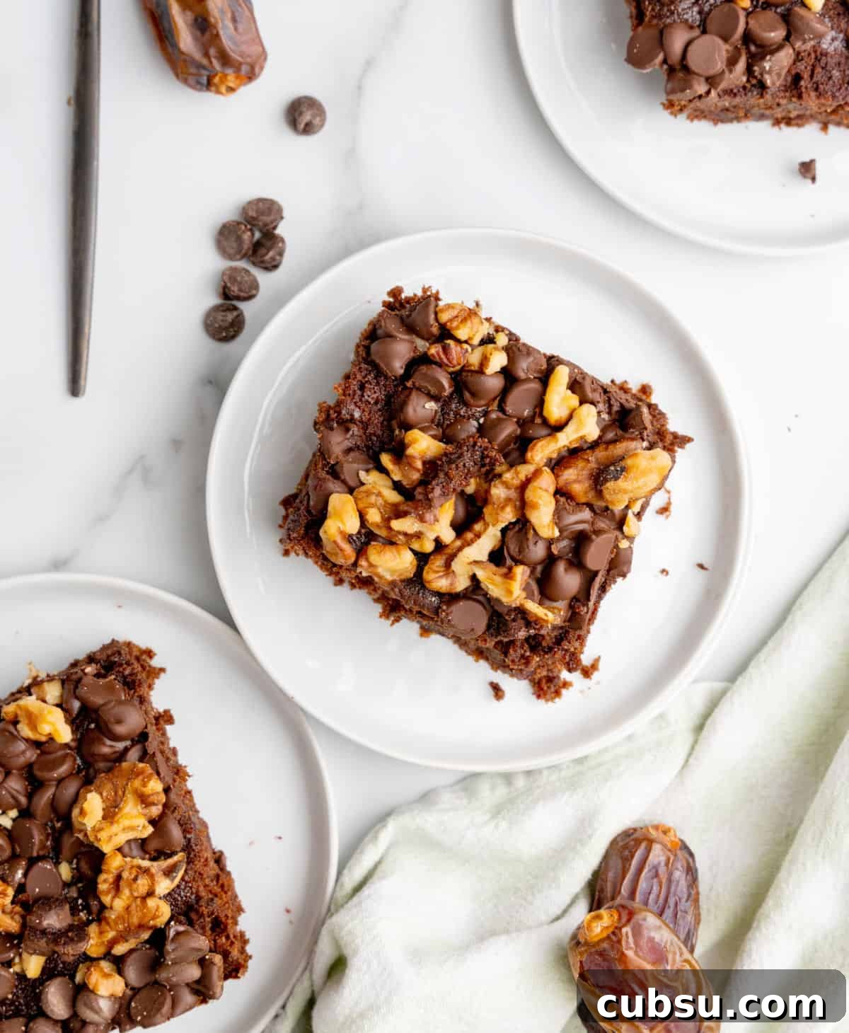 Decadent Chocolate and Date Cake Recipe for Moist Loaves 4 Top view of white plates with squares of walnut chocolate chip topped date cake on a white surface.
