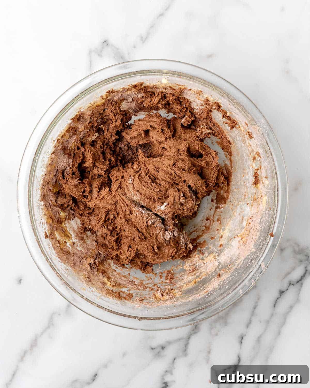 Decadent Chocolate and Date Cake Recipe for Moist Loaves 8 Glass bowl with thick chocolate cake batter. Marbled surface.