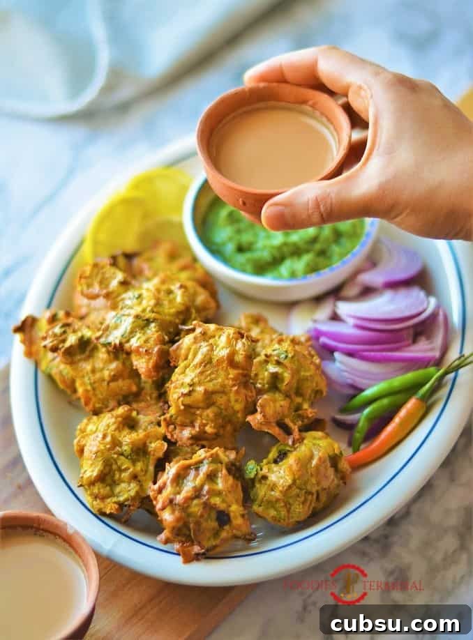 Chicken Pakora air fryer served with tea along with cilantro chuntney, onion slices, green chilies & lemon slices
