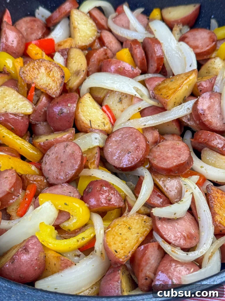 Close up of golden brown wedges of baby red potatoes, slices of onion, Kielbasa, and peppers.