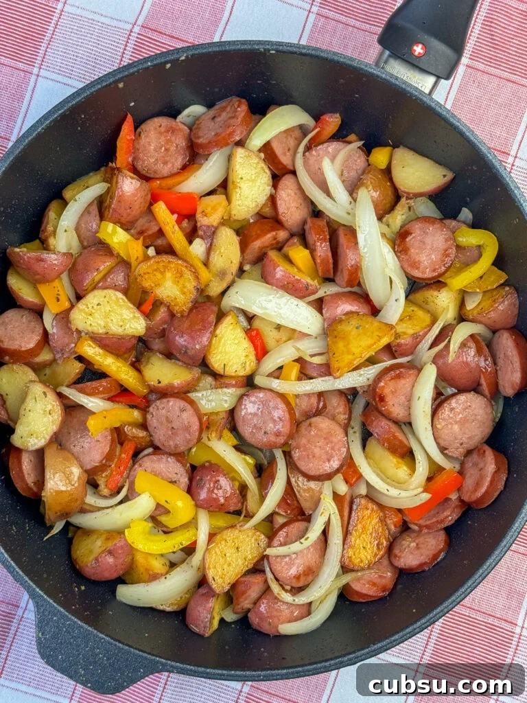 Overhead view of a flavorful skillet with a Kielbasa recipe featuring potatoes and accented with onions, peppers, salt, pepper and Italian seasoning.