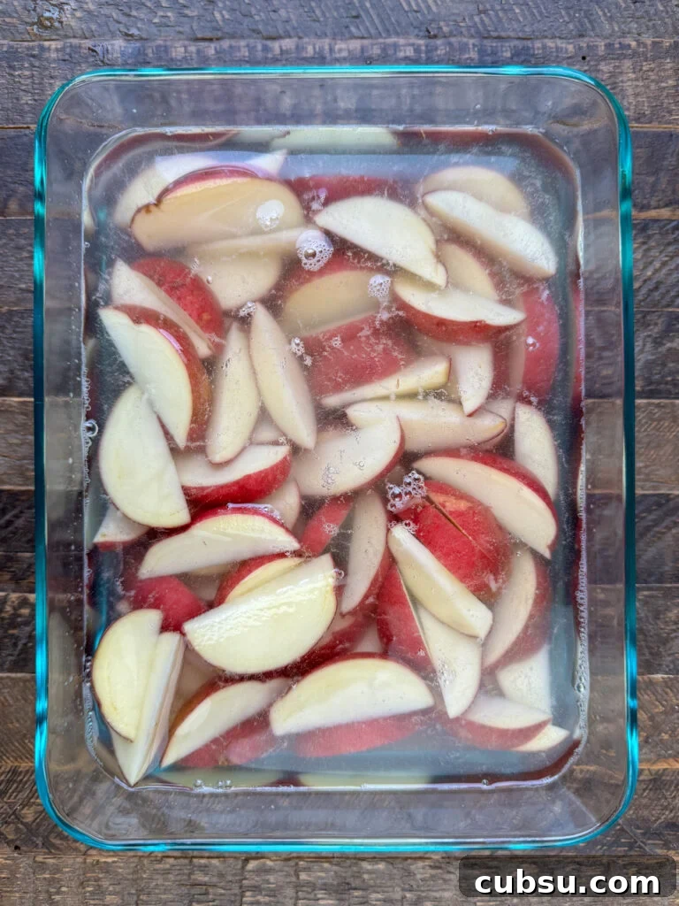 Wedges of red potatoes soaking in cold water.