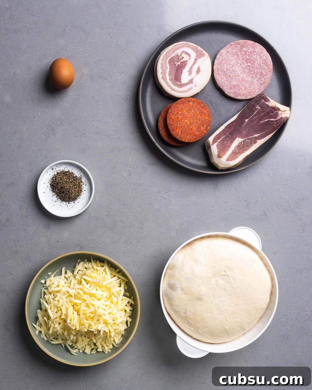 Ingredients shown: egg, pancetta, salami, pepperoni, prosciutto, black pepper, shredded provolone, and dough ball.