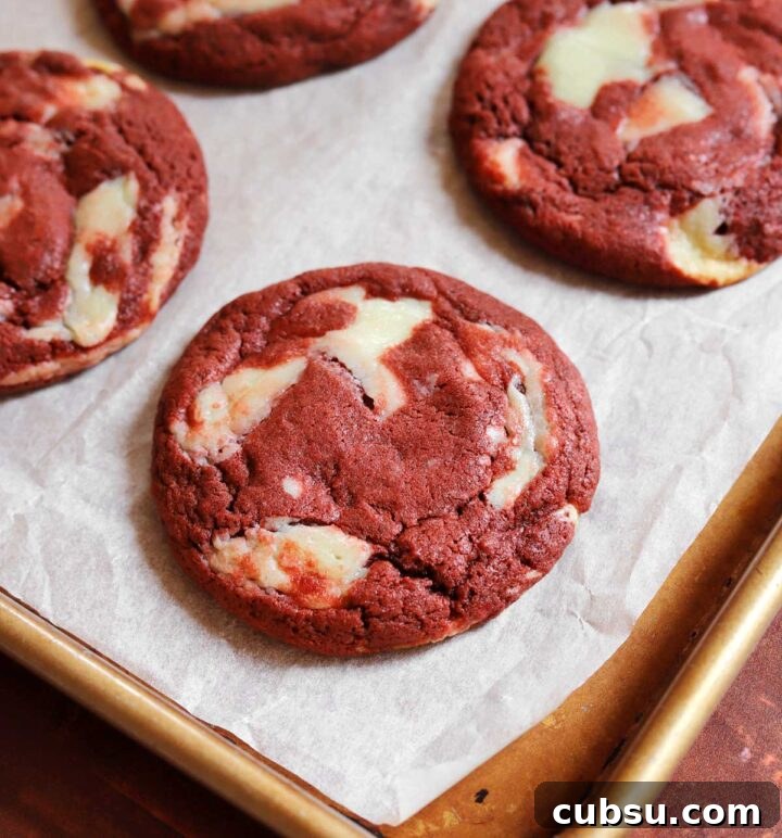 How to Make Classic Red Velvet Cookies with Cream Cheese Filling 3 red velvet cookies on parchment-lined baking sheet