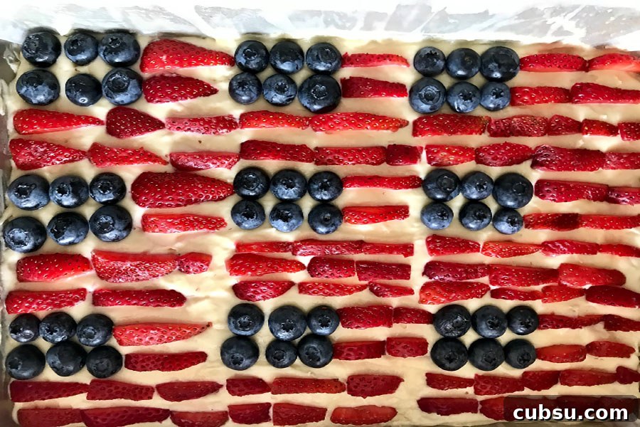 Red, White & Blue Fruit-Topped American Flag Cake Recipe 4 a beautiful american flag cake with blueberries and sliced strawberries on a white cake in a cake pan