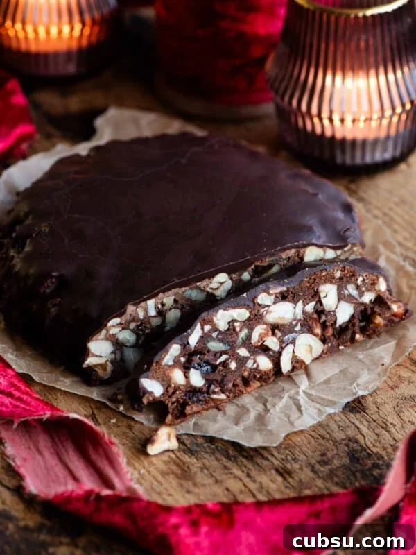 Panpepato cut into slices sitting on a wooden board with christmas red ribbon and candles.