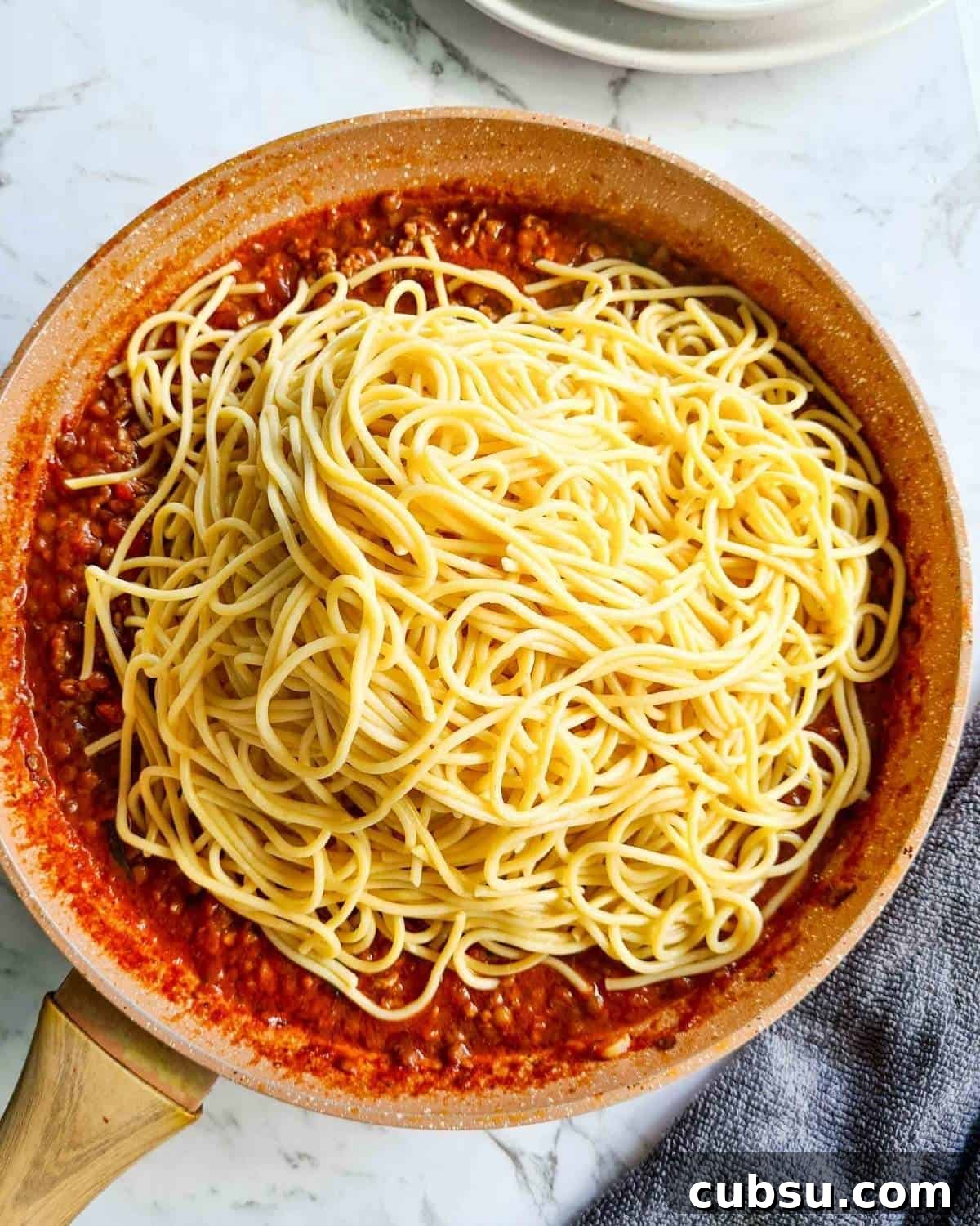 Bolognese topped with freshly cooked spaghetti, ready to be mixed through