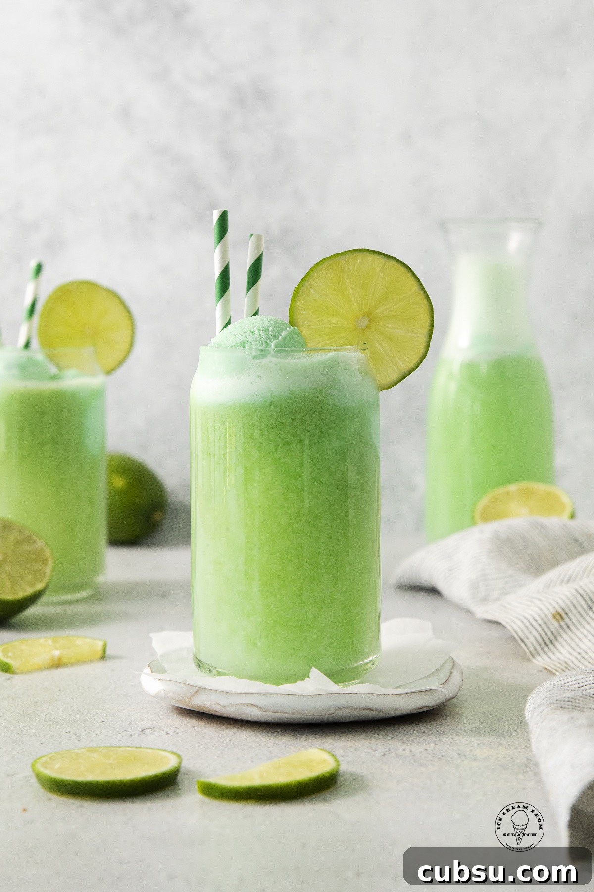 a clear glass of green punch with lime sherbet and lime wedges.