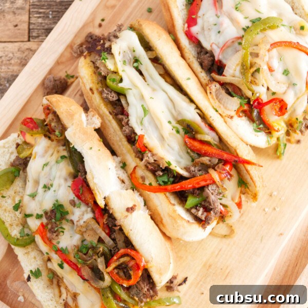 Blackstone Griddle Steak Fajitas: Flavorful Skillet Recipe 11 three philly cheesesteak sandwiches laid out on cutting board, each one filled with steak, red and green peppers, melted provolone, and cheese whiz