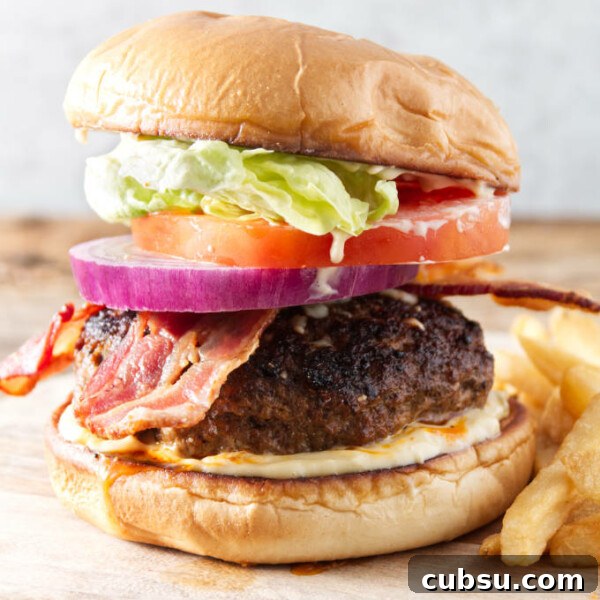 Blackstone Griddle Steak Fajitas: Flavorful Skillet Recipe 12 burger with bacon, onion, tomato, lettuce, and donkey sauce sitting on cutting board with fries