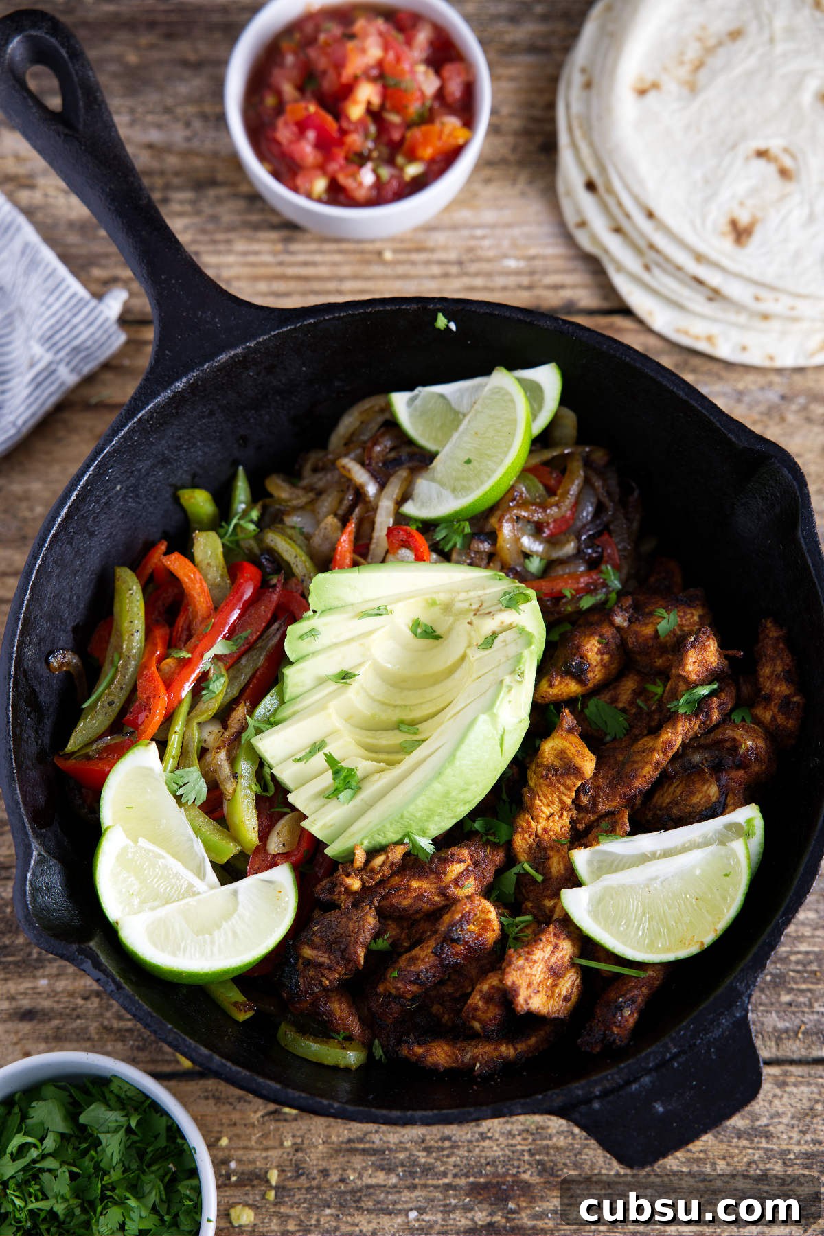 Blackstone Griddle Steak Fajitas: Flavorful Skillet Recipe 15 Cast iron filled with chicken fajitas that have been carmelized to perfection and topped with limes and avocado and surrounded by tortillas, salsa, and cilantro.