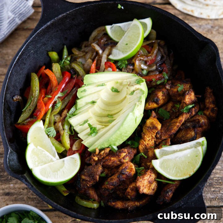 Fajitas in cast iron skillet with avocado and lime slices.