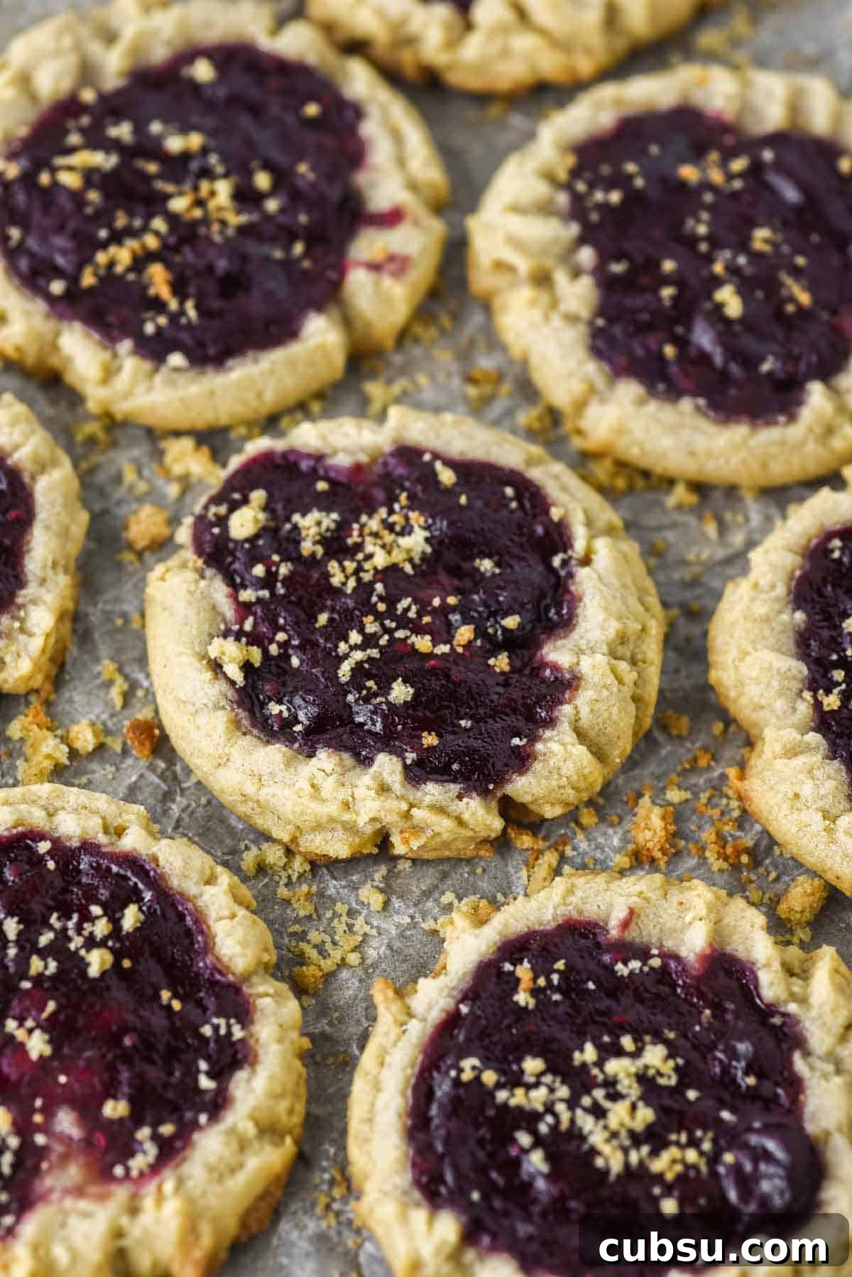 Peanut Butter and Jelly Cookie Recipe — Classic PB&J Cookies 2 close-up of peanut butter and jelly cookies on parchment-lined baking sheet
