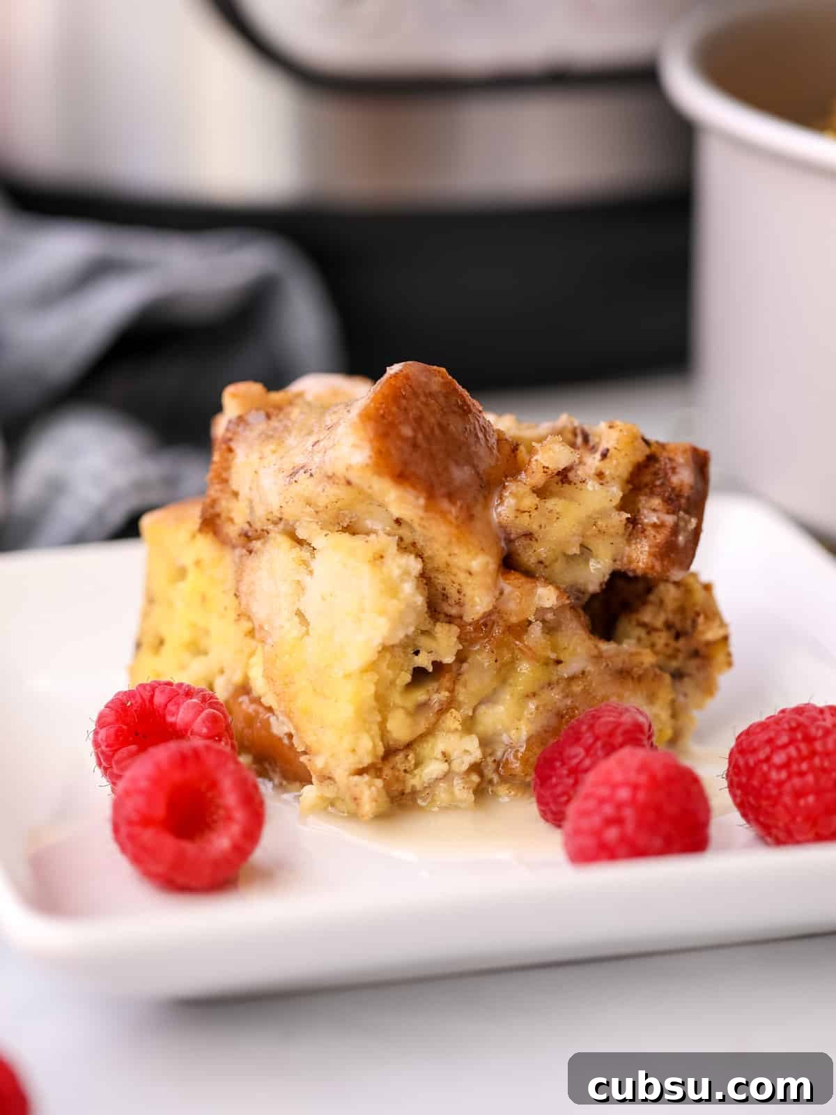 Instant Pot French Toast Casserole Slice of Instant Pot French Toast Casserole on white plate with raspberries.