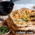 25 Creative Uses for Sourdough Discard: Recipes & Tips 10 stack of sourdough naan on a wood board with cilatro and cast iron butter melter.