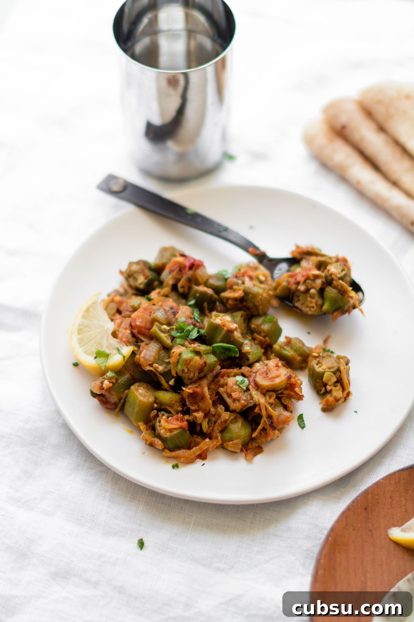 Bhindi Masala on a white plate with a black spoon
