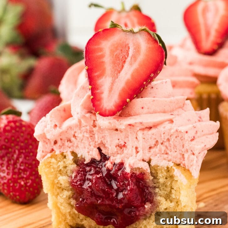 3-Ingredient Strawberry Cake Filling Recipe for Fresh Flavor 2 a gluten free vanilla cupcake filled with an easy 3-Ingredient Strawberry Cake Filling. The cupcake is cut open to show the filling and is topped with strawberry frosting and half of a fresh strawberry.