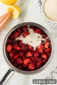 3-Ingredient Strawberry Cake Filling Recipe for Fresh Flavor 8 strawberries, sugar, and fresh lemon juice in a silver saucepan