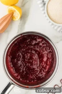 3-Ingredient Strawberry Cake Filling Recipe for Fresh Flavor 9 cooked strawberries, sugar, and fresh lemon juice in a silver saucepan to make strawberry cake filling