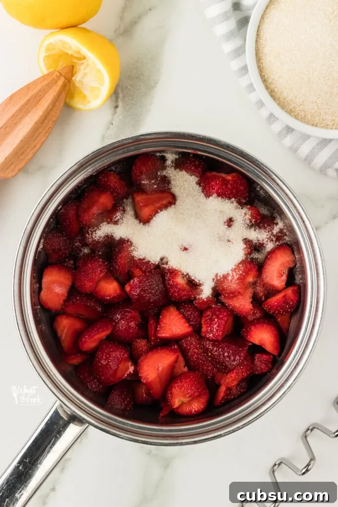 3-Ingredient Strawberry Cake Filling Recipe for Fresh Flavor 4 strawberries, sugar, and fresh lemon juice in a silver saucepan