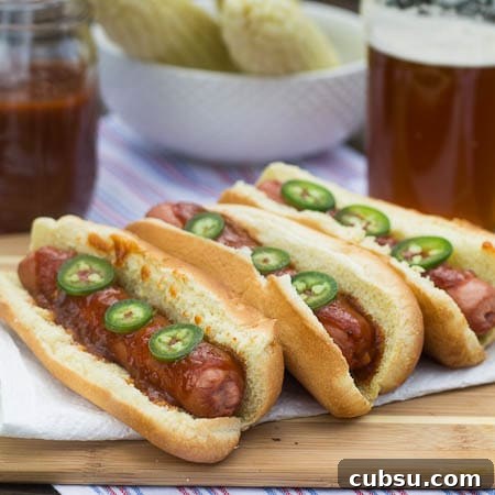 Three hot dogs topped with jalapeno slices.