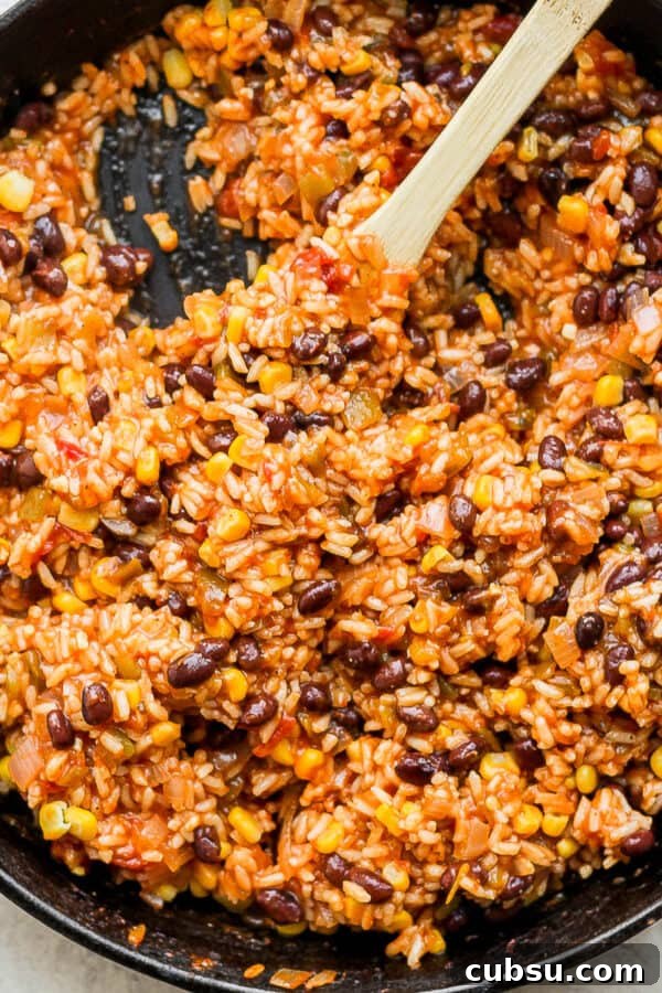 Crispy Oven and Air Fryer Rice: Step-by-Step Guide for Crunchy Rice 11 Cast iron skillet filled with salsa rice with wooden spoon sticking out.