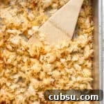 Crispy Oven and Air Fryer Rice: Step-by-Step Guide for Crunchy Rice 13 Crispy rice on a baking sheet with a wooden spatula sticking out.