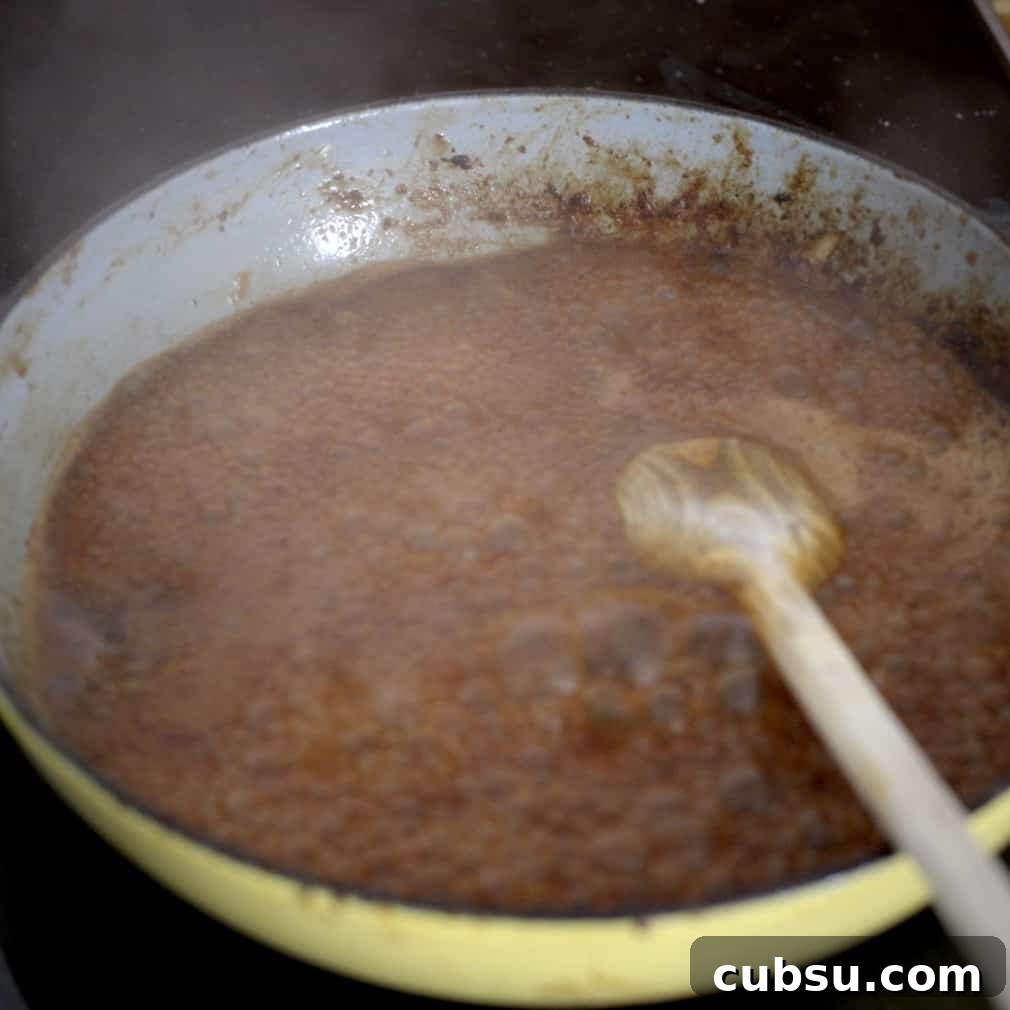 Slow Cooker Pork in Cider and Mustard Sauce 10 Steamy image of a yellow frying pan being deglazed with fiercely bubbling brown water