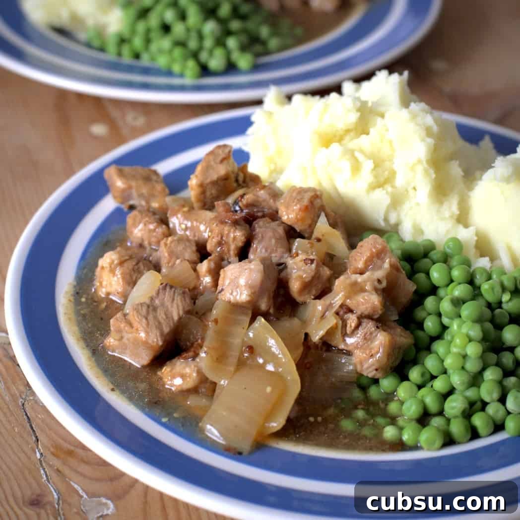 Slow Cooker Pork in Cider and Mustard Sauce 16 A blue and white plate with buttery mashed potato, green peas and pork in coder