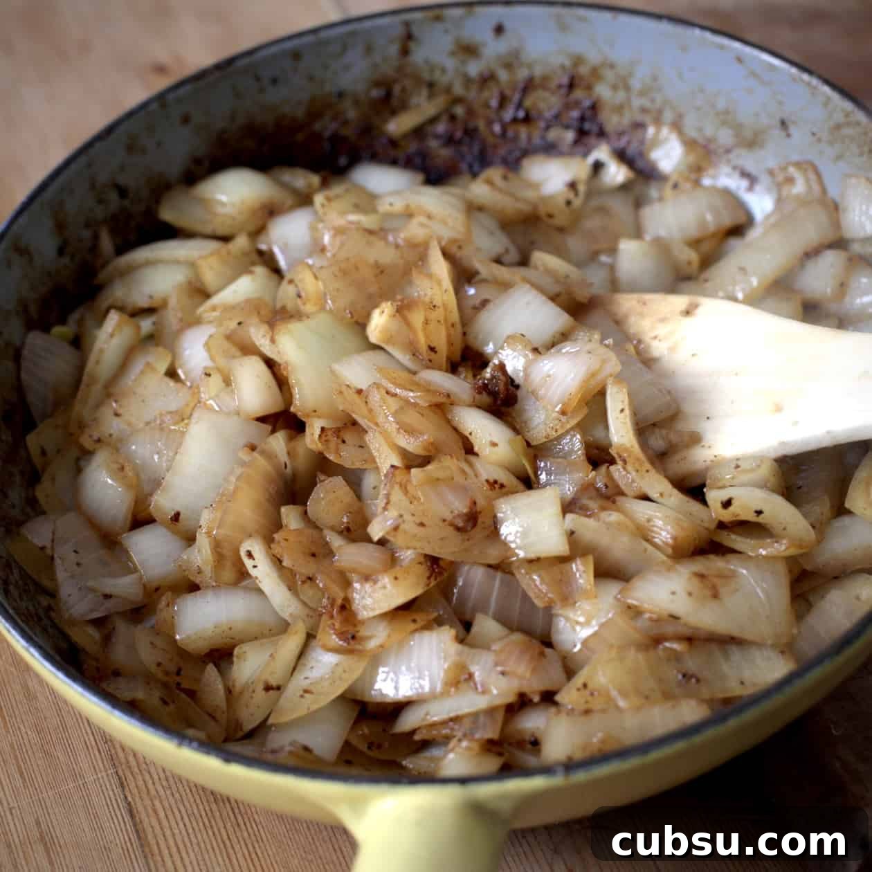 Slow Cooker Pork in Cider and Mustard Sauce 3 Yellow frying pan filled with chopped onions that are being slowly sweated into soft, brown onions